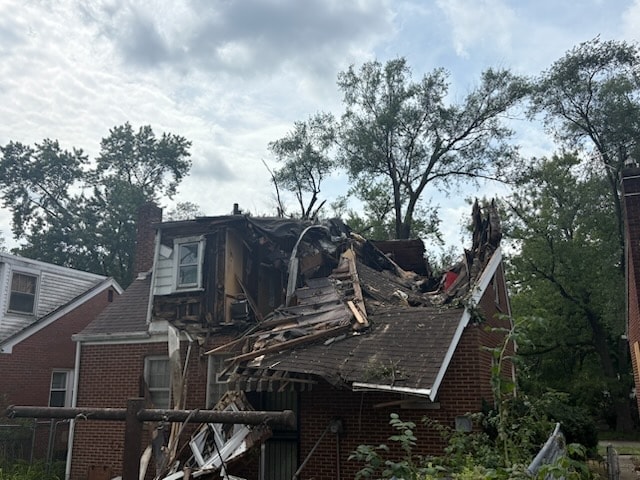 Brick home with severe storm damage from a fallen tree